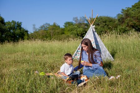 Beautiful mom with her son on a picnic rest in natureの写真素材