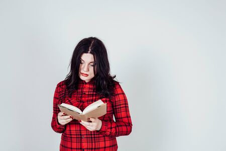 fat girl in a red shirt reads a bookの写真素材