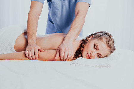 beautiful girl massage therapist makes a back massage in the spa health