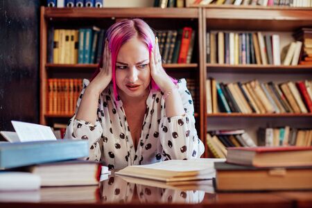 girl is preparing for the exam reads a lot of books in the libraryの写真素材