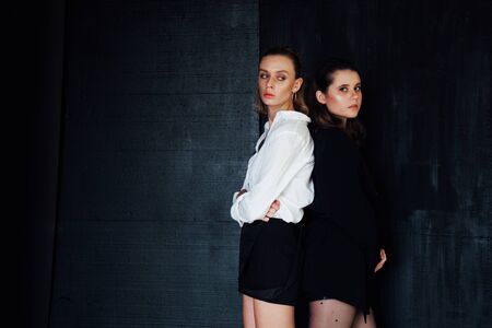 Two beautiful fashionable female girlfriends sit togetherの写真素材