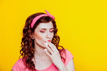 girl in pink dress pinup-style eats cream, licks fingersの写真素材