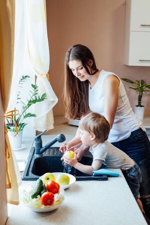 the little boy is helping mom in the kitchenの写真素材