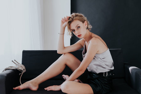 portrait of a beautiful fashionable blonde woman on a black office sofa
