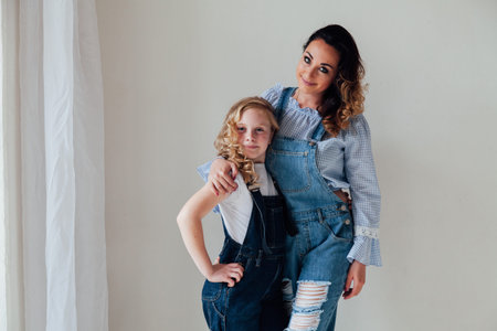Mom with little girl in denim jumpsuit play in white room