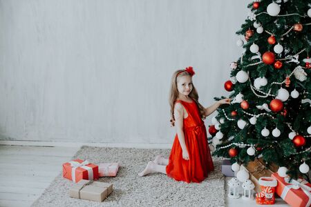 little girl opens Christmas presents new year tree decorationの写真素材