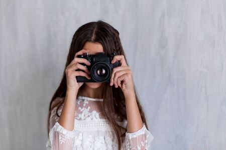 Portrait of a beautiful girl in a white dress with a cameraの写真素材