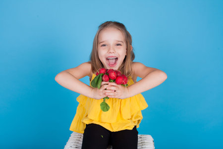 little girl with edible vegetables on a blue background
