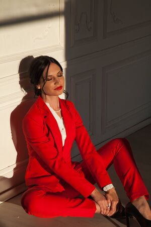 Portrait of a business woman brunette in a red business suit in the officeの写真素材