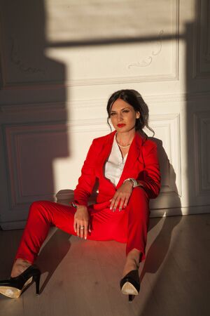 Portrait of a business woman brunette in a red business suit in the officeの写真素材