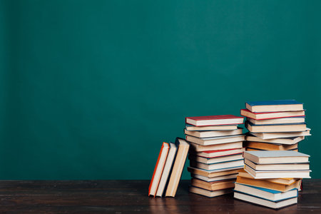 many stacks of books to teach in the school library on a green background