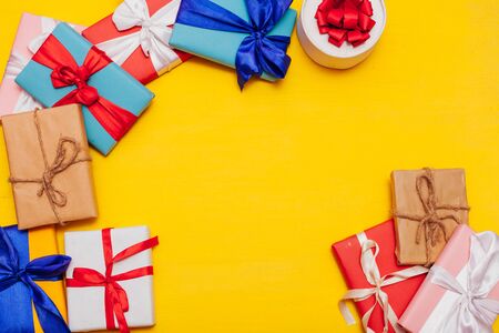 many multi-colored gifts for the holiday on a yellow backgroundの写真素材