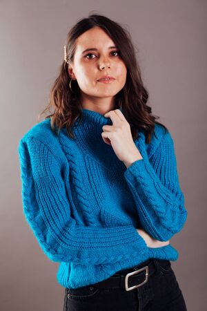 Portrait of a beautiful young fashionable brunette brunette woman in a blue sweaterの写真素材