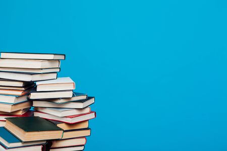 lots of stacks of educational books to teach in the school library on a blue backgroundの写真素材