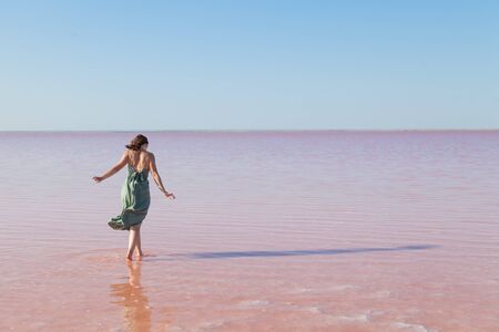 Woman in dress stands in rose water lake against blue skyの写真素材