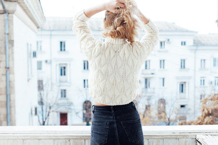 Portrait of a fashionable blonde woman in jeans and a white sweater