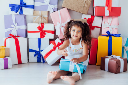 Beautiful little fashionable girl opens gifts for the holiday birthday