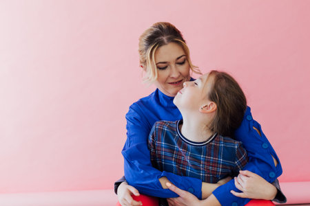 mom and daughter cuddle love family pink background