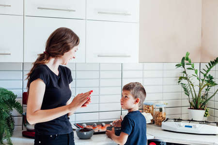 Mom pastry chef and son cook sweet cakes in the kitchenの写真素材