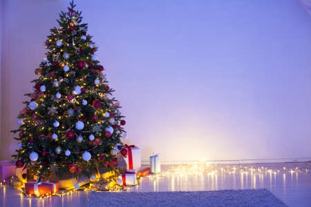 Christmas tree with gifts of garland lights at night on New Years Eve in the interior roomの写真素材