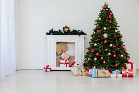Christmas tree with gifts pine new year decor the interior of the white room of the house postcardの写真素材