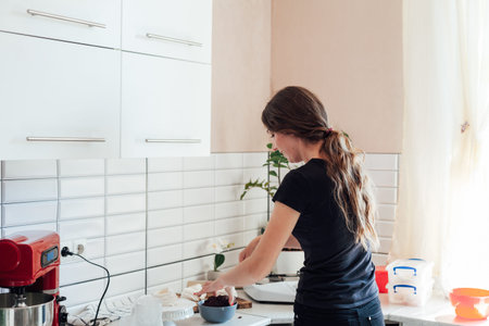 Woman cooks delicious sweet cakes with cream in the kitchen