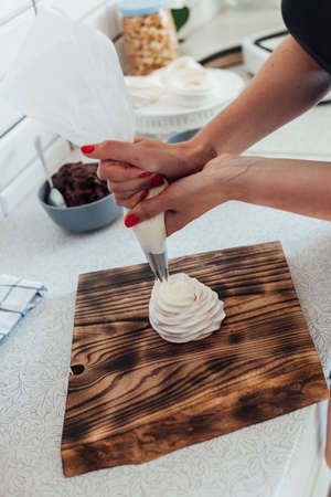 Woman cooks delicious cakes with cream in the kitchenの写真素材