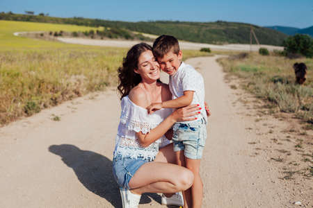 Beautiful woman mom hugs young son in nature on a walkの写真素材