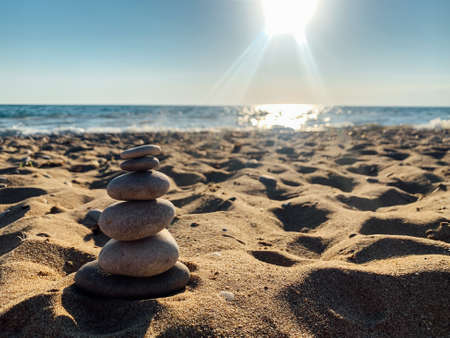 Pyramid stones balance on the sand of the beach. The object is in focusの写真素材
