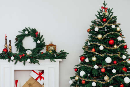 Christmas tree with gifts by the fireplace for the new year decor of the houseの写真素材