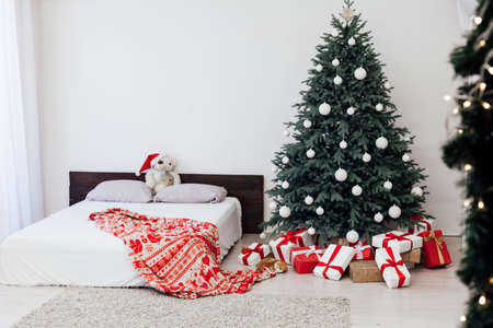 New year bedroom decor with Christmas tree bed with gifts and garlands interiorの写真素材