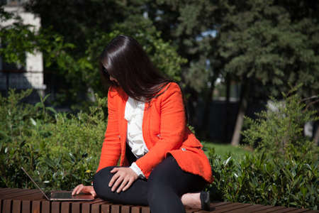 Beautiful business brunette woman works on laptop online in the parkの写真素材