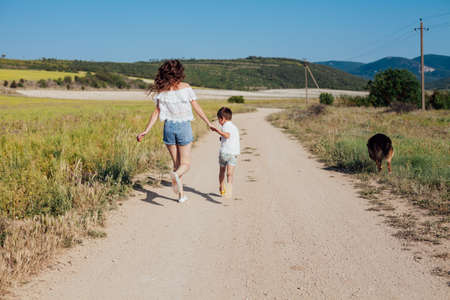 Mom with young son on a walk in the field of summer family loveの写真素材