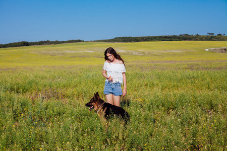 Beautiful woman on a walk in a field with her dog