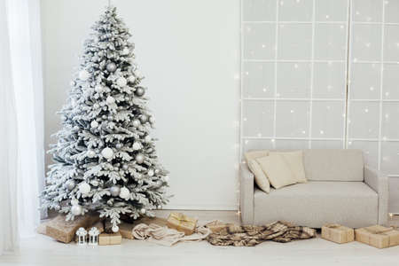 Home interior. A room with a beautiful snowy Christmas tree and gifts under this tree.の写真素材