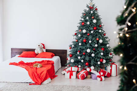 bedroom with bed decor new year and beautiful Christmas tree with giftsの写真素材
