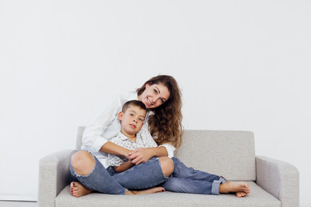 Mom and son sit on the sofa at home in a white roomの写真素材