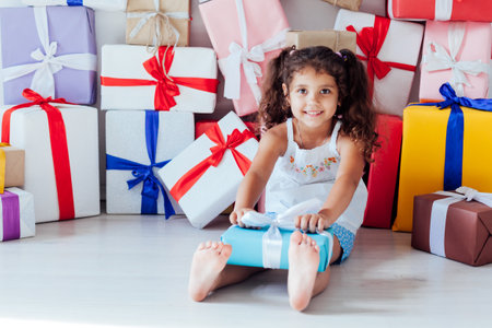 Beautiful little curly fun girl and lots of birthday giftsの写真素材
