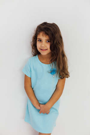 Beautiful little curly girl in a blue dressの写真素材
