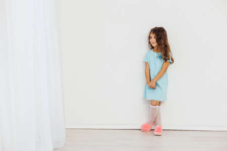Beautiful little curly girl 5 years old in a blue dress on a white backgroundの写真素材