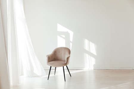 one beige chair in the interior of an empty white room with a windowの写真素材