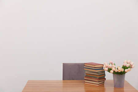 a stack of books and a bouquet of tulips on a table in a white officeの写真素材