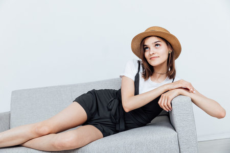 Beautiful fashionable woman in dress sits on the couchの写真素材