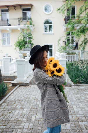 beautiful fashionable woman in a black hat with yellow sunflower flowersの写真素材