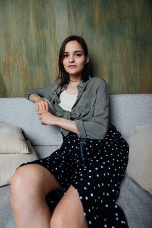 Beautiful fashionable woman in dress sits on the couch
