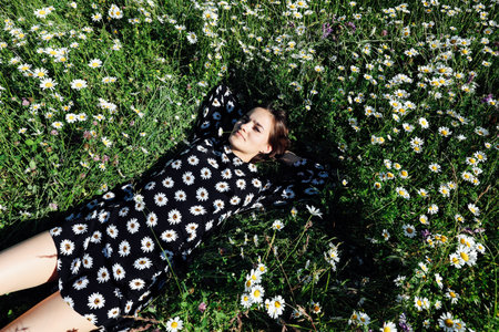 Beautiful woman lies in the grass on a field of daisies