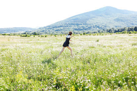 Beautiful young happy woman runs on the field of daisiesの写真素材