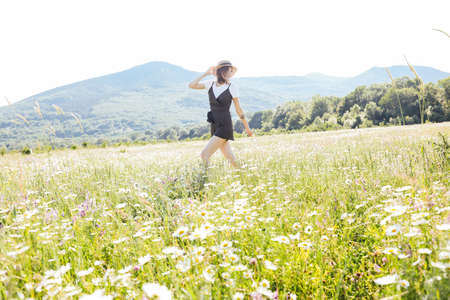 Beautiful young happy woman runs on the field of daisiesの写真素材