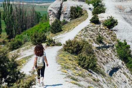 brunette woman walking along a mountain road looks at the nature of the journeyの写真素材