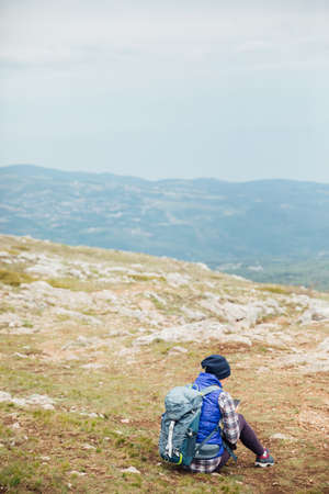 a woman looks at a smartphone on top of a mountain on a hiking tripの写真素材